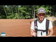 a man standing on top of a wooden roof holding a camera and wearing a hat