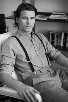 a man sitting in a chair wearing suspenders