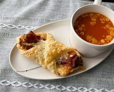 a white plate topped with food next to a cup of soup