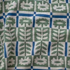 a green and white quilt with flowers on it