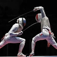 two men in fencing gear are jumping over an obstacle course with one holding the bar