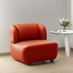 an orange chair sitting next to a table with a vase on it and a white flower pot