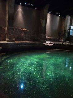 an indoor swimming pool with green algae in the water and lights shining on the floor