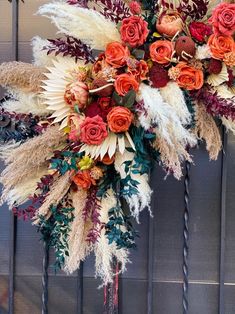 an arrangement of dried flowers and feathers on a door handle in front of a wall