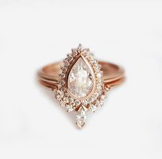 a ring with a pear shaped diamond surrounded by smaller diamonds on the band and inside