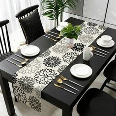 a black and white dining table set with plates, silverware and flowers on it