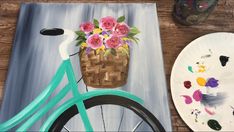 a painting of a bicycle with flowers on it next to a paper plate and paintbrush