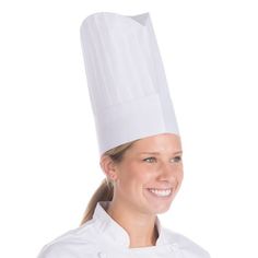 a woman wearing a chef's hat and smiling at the camera while standing in front of a white background