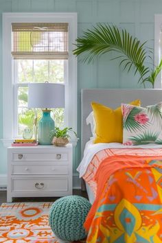 a bedroom with blue walls, white furniture and colorful pillows on the bedding is decorated with palm leaves