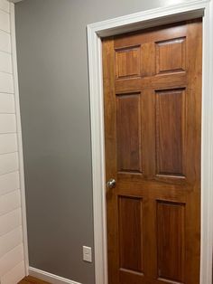 an empty room with a wooden door and hard wood floor