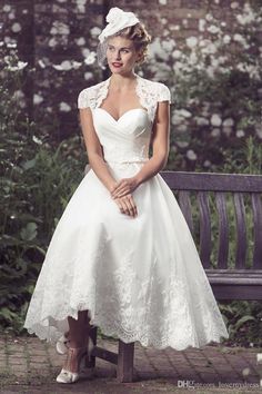 a woman sitting on a bench wearing a white dress and headpiece with flowers in the background