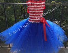 a red, white and blue tutu dress hanging on a rail with trees in the background