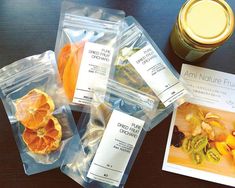 several packaged food items on a table next to a jar of oranges and other fruit