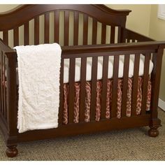 a baby crib with a white blanket on it's side and a brown wooden frame