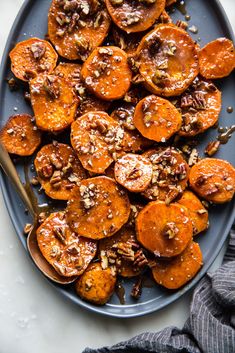 a blue plate topped with sweet potatoes covered in nuts and pecans next to a fork