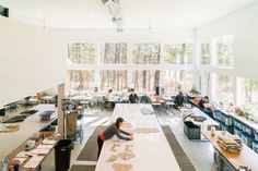 an office with people working on desks in the middle and lots of windows above