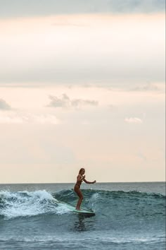 a woman riding a wave on top of a surfboard in the middle of the ocean