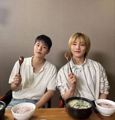 two people sitting at a table with bowls and spoons