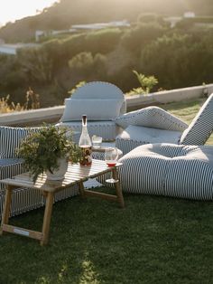 an outdoor seating area with striped cushions and a bottle of wine on the coffee table