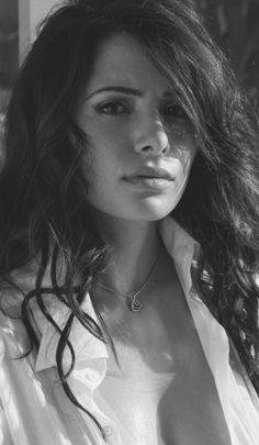 black and white photo of a woman with long hair wearing a shirt, posing for the camera