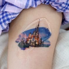 a woman's thigh with a castle tattoo on it