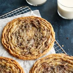 three cookies sitting on top of a cooling rack next to a glass of milk