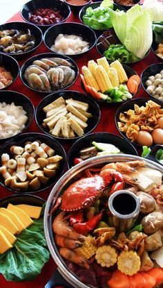 an assortment of food is displayed in bowls on a red tablecloth with other foods