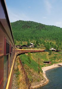 a train traveling down tracks next to a lush green hillside