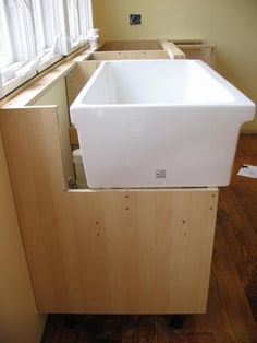 a white sink sitting on top of a wooden counter next to a window in a kitchen