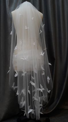 a veil with white birds on it is sitting on a mannequin's head