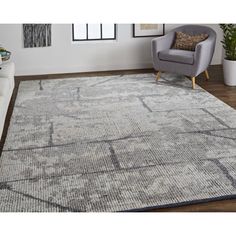 a large rug with an abstract design in grey and blue tones, on a wooden floor