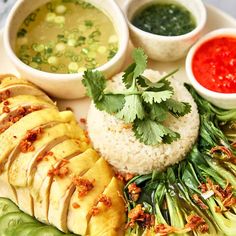 a white plate topped with rice, meat and veggies next to dipping sauces