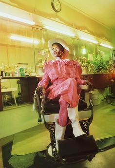 a person sitting in a chair wearing a pink dress and hat