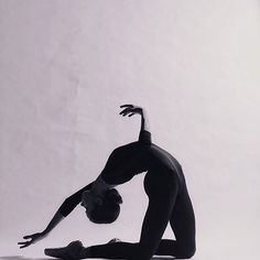 a woman is doing a handstand on one leg while standing in front of a white background