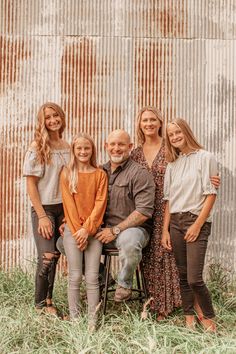 a family poses in front of an old corrugated wall