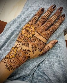 a henna on someone's hand that is decorated with flowers and leaves in the middle