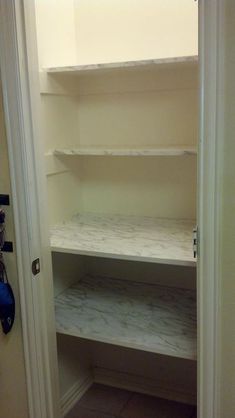 an empty walk in closet with white shelves