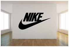 a wall that has a nike logo on it in a room with hardwood floors and windows