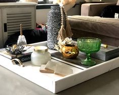 a tray with some vases and other items on it in front of a couch