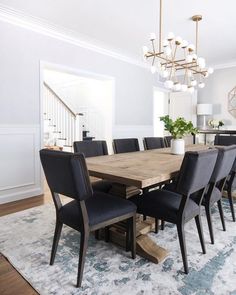 a dining room table with black chairs and a chandelier