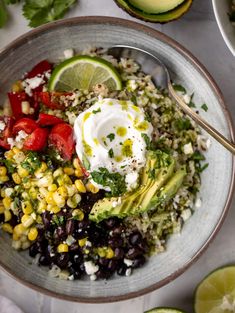 a bowl filled with rice, black beans, avocado, and sour cream