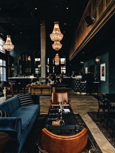 a large room with couches, tables and chandeliers hanging from the ceiling