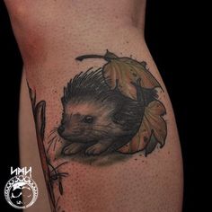 an animal tattoo on the side of a woman's leg, with leaves around it