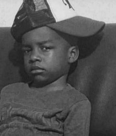 a black and white photo of a young boy wearing a hat with a bird on it