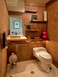 a bathroom with a toilet, sink and shelves on the wall in it's corner