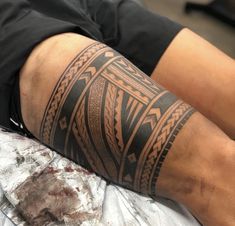 a man with a tattoo on his arm laying on a bed next to a piece of paper