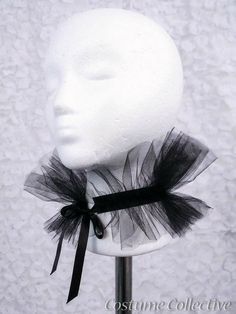 a white mannequin head with black tulle and ribbon around the neck on a stand