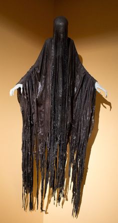 a mannequin wearing a black shawl with fringes on it's shoulders