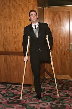 a man in a suit and tie holding crutches