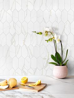 a vase with flowers and lemons on a marble table